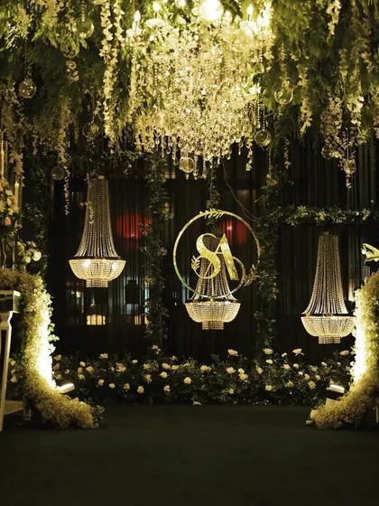 A full view of the romantic, dimly lit photo point, where hanging florals, chandeliers, and a custom monogram create a perfect backdrop for couple portraits.