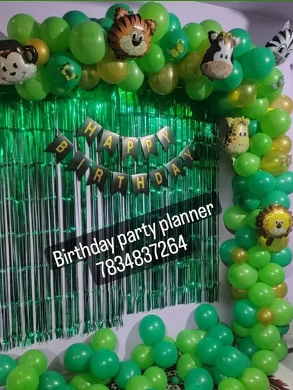 A simple and effective jungle theme decoration for a home party, using a green fringe curtain and a balloon arch with animal foil balloons.