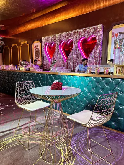 A stylish bar for a love-themed party, with a quilted turquoise front and large, metallic red heart balloons, combining chic design with playful romance.