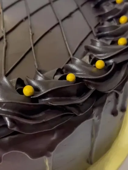 A close-up of the rich chocolate piping and the checkered pattern on top of the drip cake.