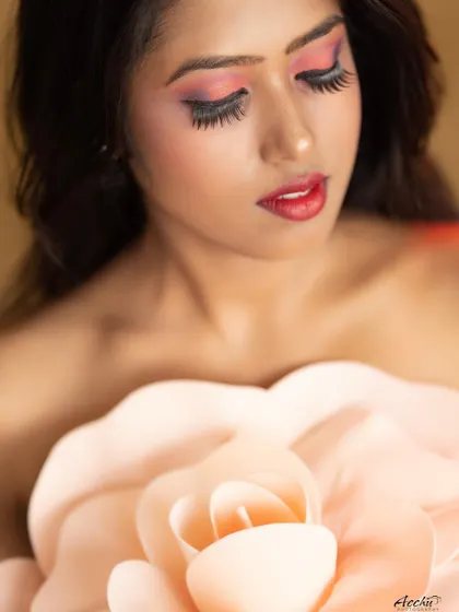 A conceptual beauty shot using a large prop flower. This close-up focuses on the makeup and the artistic composition, creating a soft and imaginative portrait.