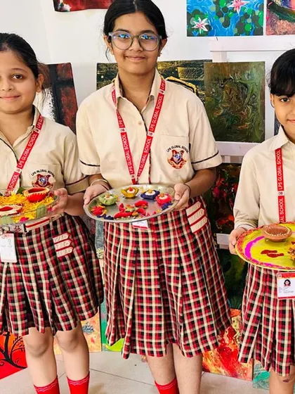 Three students hold up the decorative puja thalis they prepared for the Diwali competition. This activity allows them to express their creativity while learning about cultural traditions.