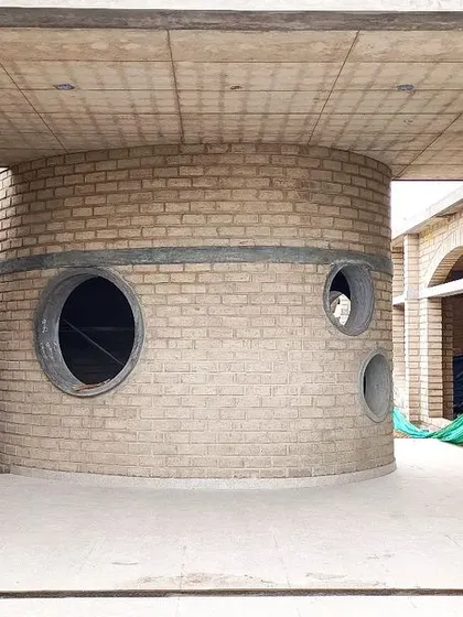 The central rotunda at Sai Kirupa Special School under construction, showing the exposed brickwork and circular window openings that define this key gathering space.