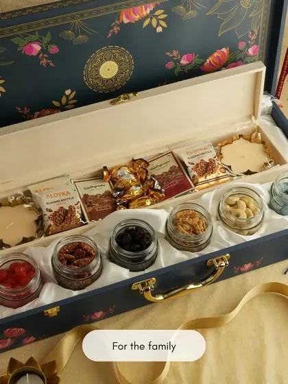 This elegant, long wooden box is a premium gifting option for families during Diwali. It's filled with small jars of dry fruits and assorted chocolates, designed for sharing.