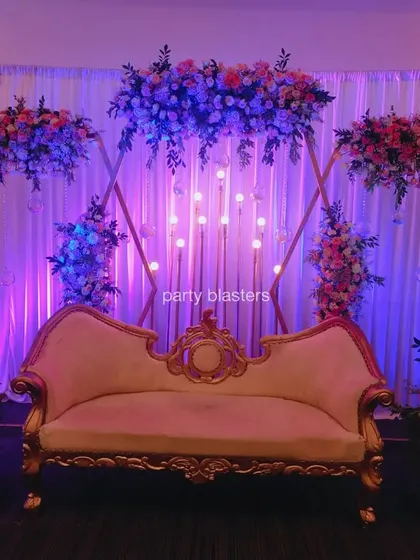 An elegant stage for a wedding anniversary. The design features a geometric gold frame, beautiful floral arrangements, and soft lighting for a romantic and sophisticated look.