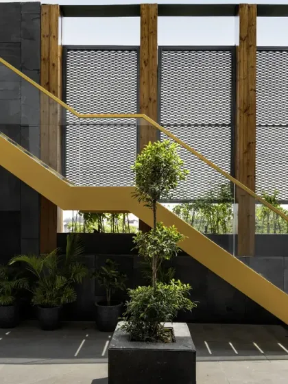 A bold yellow staircase on the terrace of The House of Dancing Screens. This functional element also acts as a sculptural piece, adding a pop of color against the dark stone walls and mesh screens.
