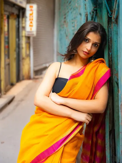 Leaning against a wall in a narrow lane, this portrait has a relaxed yet direct feel. The out-of-focus background hints at the city's depth.
