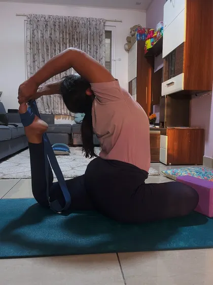 A student using a strap to work on her shoulder opening in a deep backbend. Props are essential tools for making advanced poses more accessible.