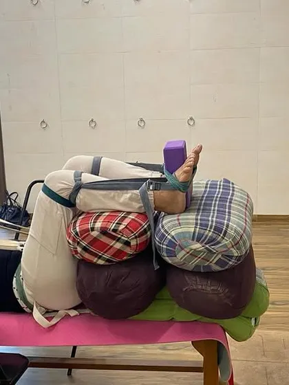 An advanced therapeutic setup for deep relaxation and hip opening. The body is completely supported by a bench, bolsters, and belts.