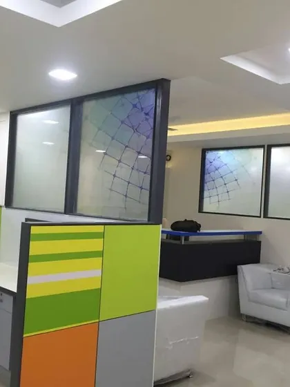 Another angle of the office interior, showing the arrangement of cubicles and a small seating area.