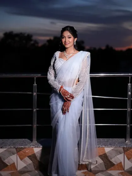 The bride posing against the twilight sky. Her ethereal look is enhanced by a soft, glowing makeup application and a beautiful powder blue saree.