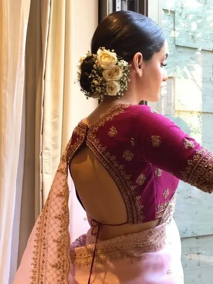 A side view of a bride with a floral bun, showing how the hairstyle can be both soft and structured. It's a perfect choice for a classic bridal look.