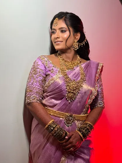 A beautiful shot against a red background, making the lavender saree and the flawless makeup pop.