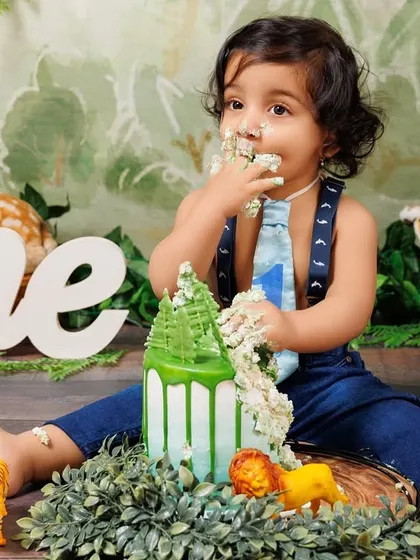 The aftermath of a fun cake smash! This little boy is covered in cake and happiness after his jungle-themed celebration.