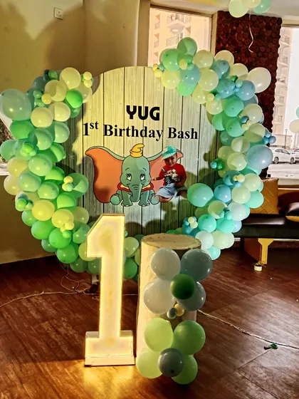 A cute Dumbo-themed first birthday bash with a heart-shaped balloon frame and a light-up number '1'.