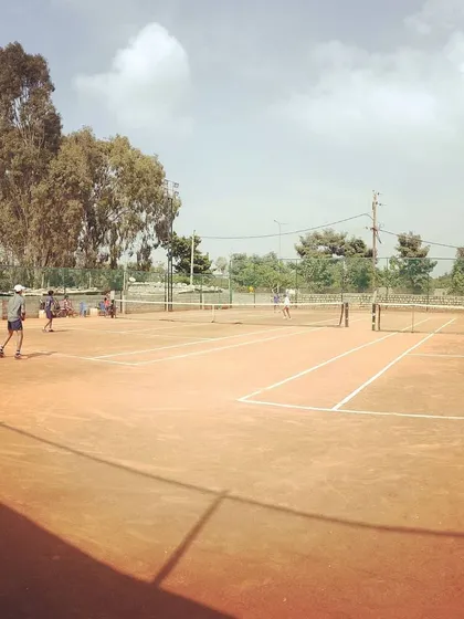 Players competing on the clay courts under a partly cloudy sky during the UTR Tour.