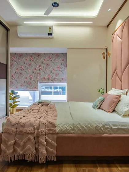 A full view of the pink bedroom, showing the harmony between the statement headboard, the sliding glass wardrobes, and the warm wooden flooring. The room feels luxurious and comfortable.