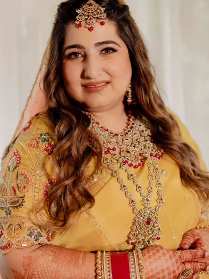 A soft and radiant makeup look for this bride's special day. We chose warm tones for her makeup to complement her beautiful yellow outfit, paired with soft waves and a maang tikka.