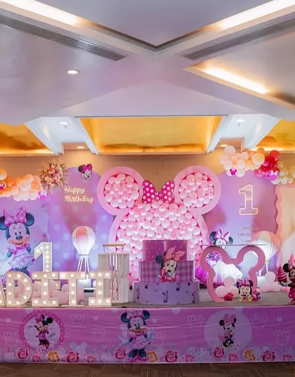A full stage view of a beautiful Minnie Mouse first birthday. The large balloon mosaic of Minnie's head is a real showstopper and creates a fantastic backdrop for photos.
