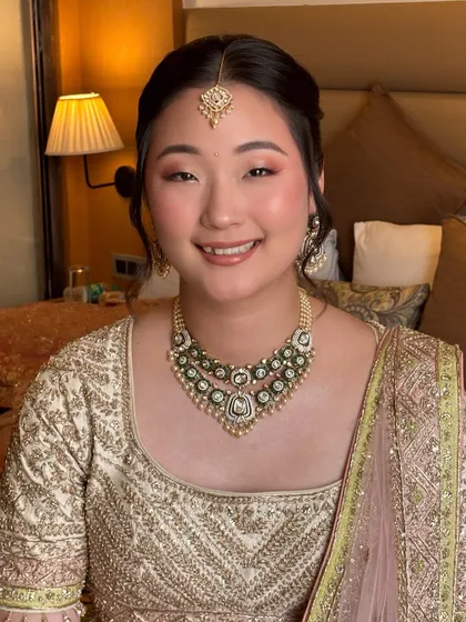 A beautiful smiling portrait. The soft pink eyeshadow and glowing cheeks give her a fresh, youthful, and celebratory look.