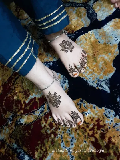A top-down view of the mandala feet henna, looking elegant against the rich blue fabric.