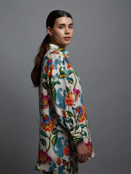 A profile shot of a vibrant, floral-printed kurta. The clean grey background makes the colourful pattern pop, and the model's simple, elegant pose highlights the garment's silhouette.