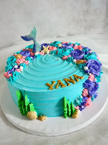 A fin-tastic mermaid cake with a beautiful buttercream wave texture and a crescent of colorful piped details.