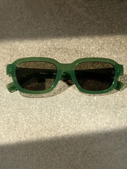 A close-up of the Miniso sunglasses, focusing on the texture and color of the frame under dramatic lighting.