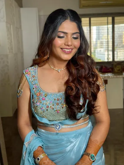 A happy client ready for her event. The hairstyle is designed to complement the intricate blouse and delicate jewelry.