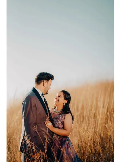 A beautiful shot of a couple in a field of golden grass at sunset. The warm light and their happy expressions make this a perfect golden-hour portrait.