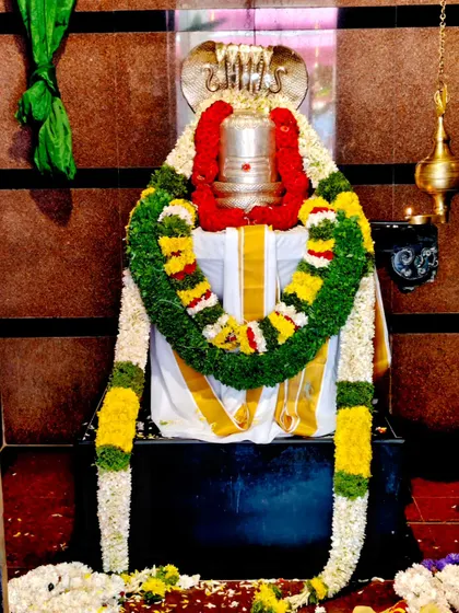 A Shiva Lingam decorated with a traditional cloth and a beautiful garland of fresh flowers for a temple ceremony.