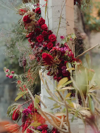 A close-up of the wild, textural floral arrangements we created for the pillars at the Bunt ceremony. We combined deep red roses with exotic protea and wispy grasses for a dramatic and artistic effect.