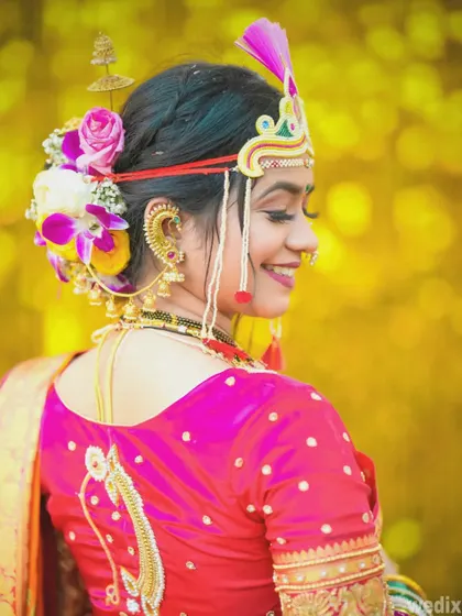 A smiling profile shot of the bride, highlighting the beautiful floral arrangement in her hair and her traditional jewellery.