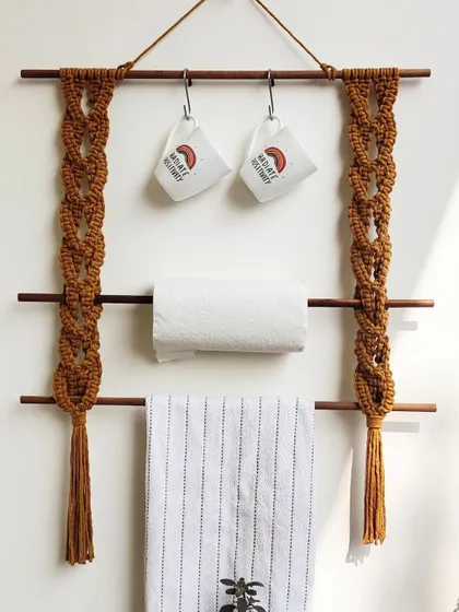 This macrame kitchen hanger is a great space-saver. It has two wooden dowels for hanging kitchen towels or paper towel rolls, and you can add hooks to the top bar for mugs or utensils.