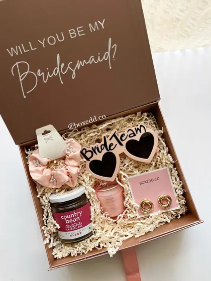 A fun and stylish "Will you be my Bridesmaid?" proposal box. This hamper includes 'Bride Team' sunglasses, a scrunchie, gourmet coffee, and other treats, all packed beautifully to get your friends excited for the journey ahead.