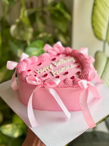 A side view of the pink birthday heart cake, showing how the ribbons cascade down the sides for a soft and celebratory balletcore look.