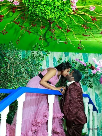 A romantic maternity photo of a couple sharing a kiss on a bridge in our whimsical, forest-themed studio set.