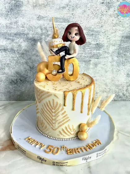Golden and glorious at 50! This elegant white and gold drip cake is topped with a custom figurine.
