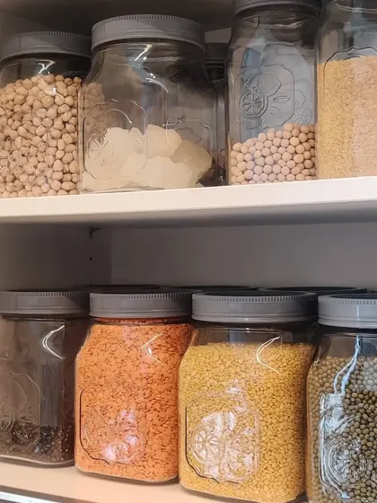These glass jars with grey lids are perfect for pantry staples. Storing items like chickpeas, lentils, and grains in uniform containers creates a cohesive and tidy look on open shelves.