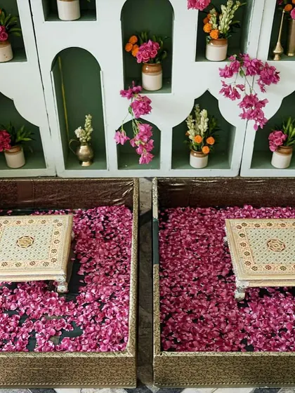 The unique urli-style seating for the haldi ceremony, filled with a bed of vibrant pink petals, set against a backdrop of jharoka-style niches.