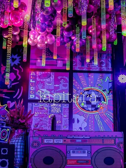 A corner of the neon party venue, showing the layered effect of glowing props, a boombox, and hanging neon sticks.