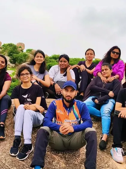 A group of trekkers resting on a large rock during the Anthargange Cave Exploration trek. This trail offers a unique mix of hiking and caving.