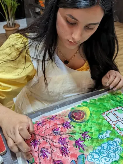 A participant working on a colorful, whimsical abstract painting of a garden scene.