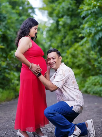 A joyful and candid moment during an outdoor maternity shoot. The father-to-be listens to the baby bump with a huge smile, capturing the happiness of this special time.