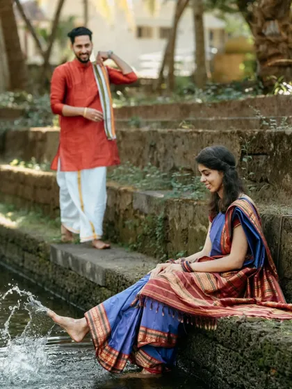 A playful moment at a temple pond, where the bride splashes water with her feet, and her partner looks on with a smile.