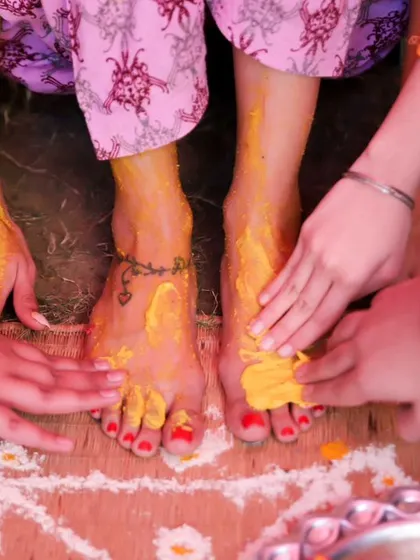 A beautiful photo showing multiple hands applying turmeric to the bride's feet. It symbolizes the love and blessings being showered upon her by her family and friends.
