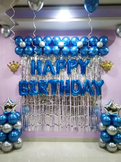 A simple yet elegant birthday backdrop in blue and silver. The decoration features balloon pillars and a flower-shaped balloon garland.
