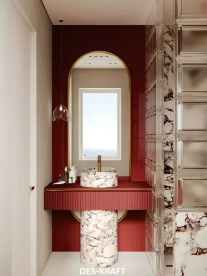 A bold and luxurious powder room with a dramatic crimson accent wall, a unique pedestal sink made of veined marble, and a glass block feature wall.