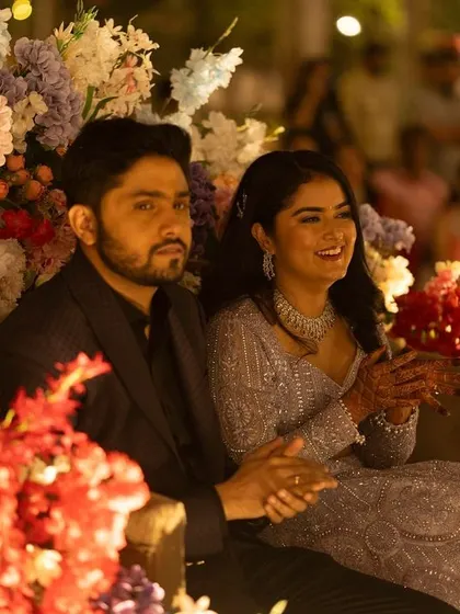 The happy couple at their Sangeet. The bride's makeup is soft and romantic, complementing the beautiful floral decor.