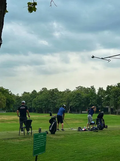 A group of three golfers practicing together, with their bags and equipment ready for a full session.